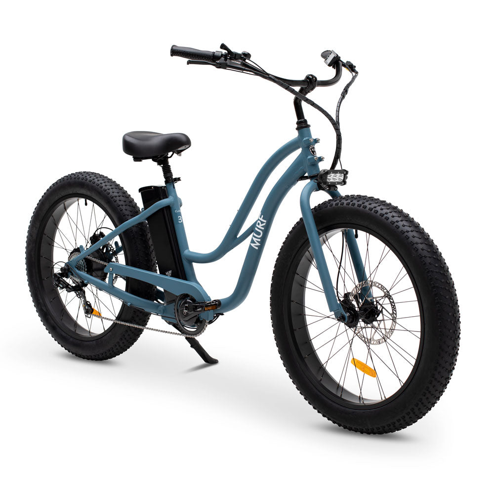 A step-through electric fat bike in blue color with fat tires and a control screen on the handlebars.