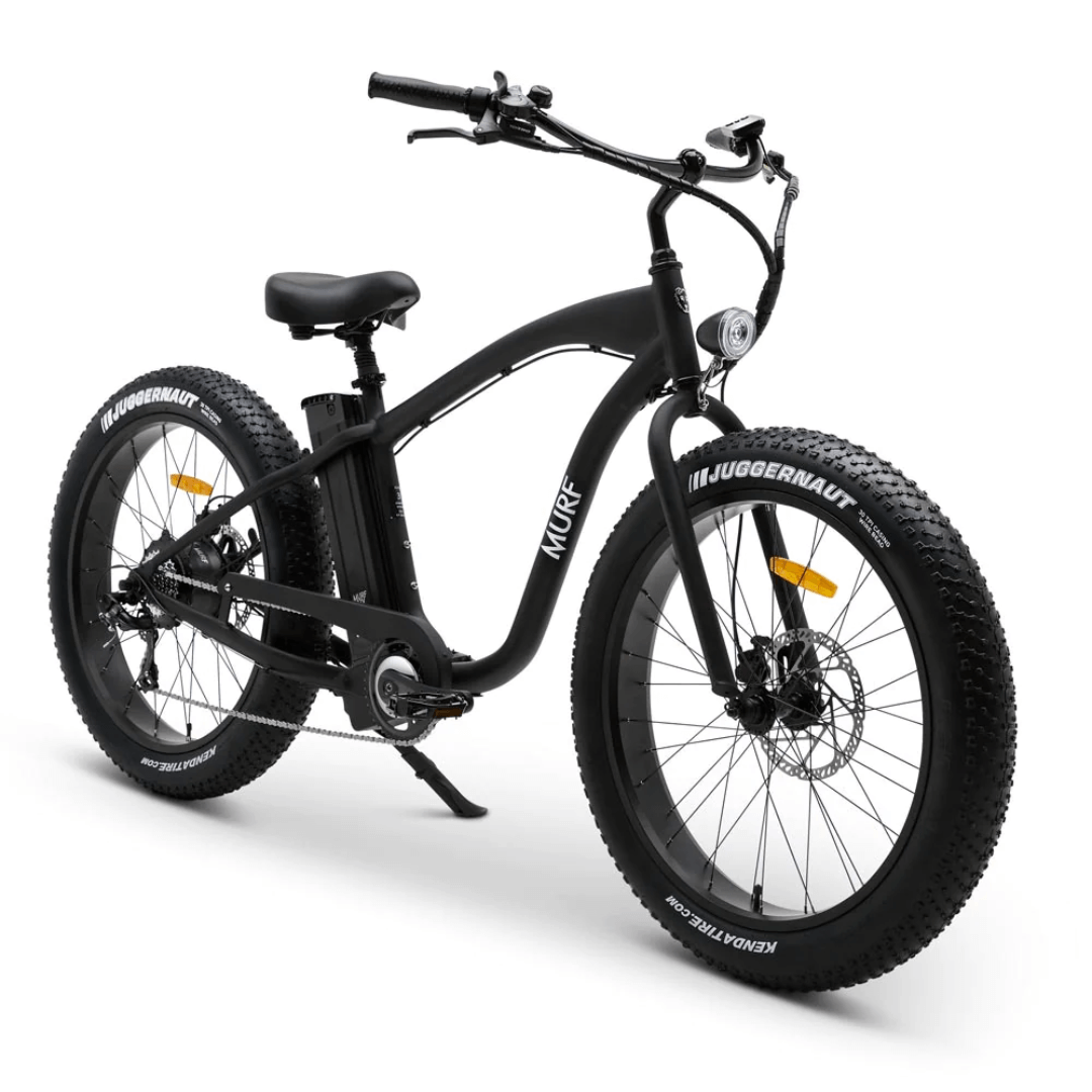 A fat tire electric beach cruiser bicycle with hydraulic disk brakes and a thumb throttle, mounted on large black tires and a classic beach cruiser frame.