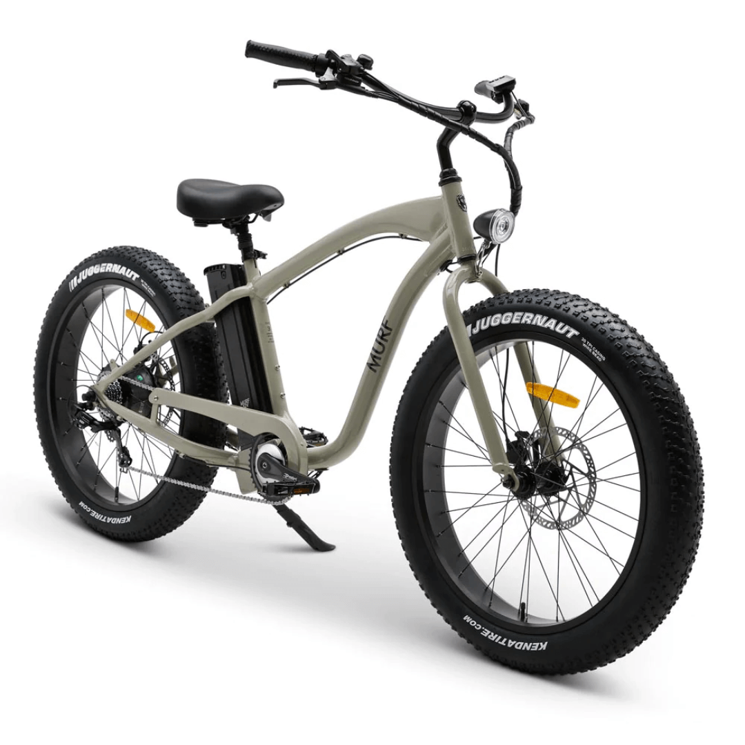 A fat tire electric beach cruiser bicycle with hydraulic disk brakes and a thumb throttle, mounted on large black tires and a classic beach cruiser frame.